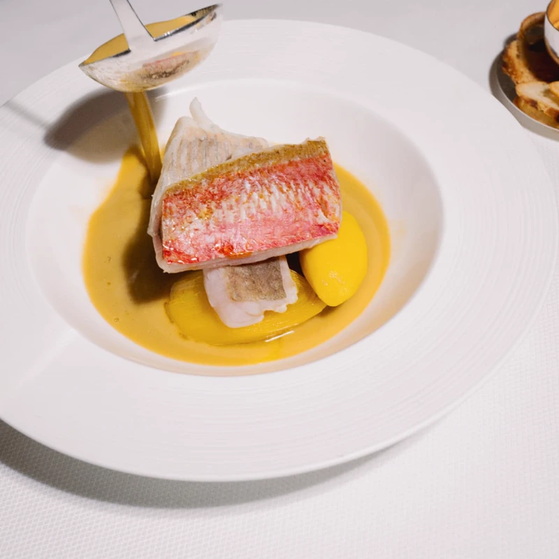 Broth poured tableside over a dish at Mazarine restaurant, Mayfair London
