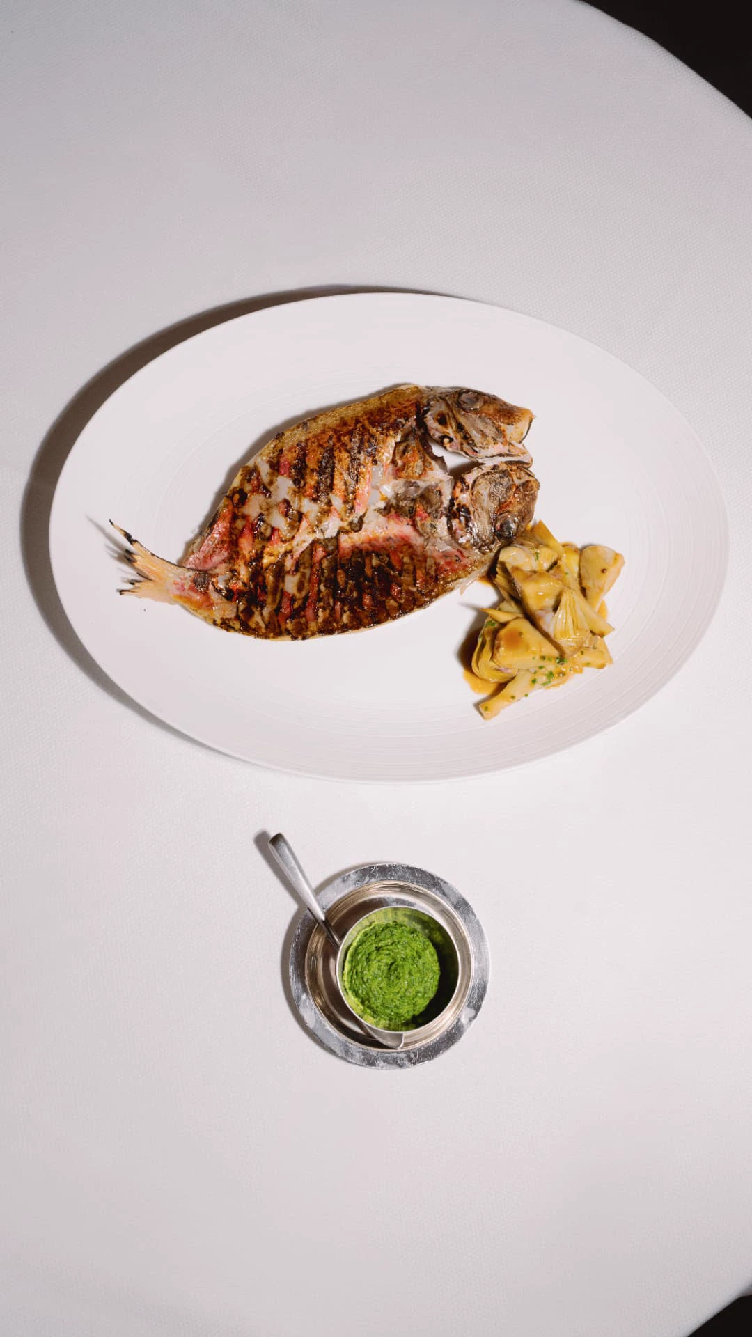 Grilled whole fish with artichokes and herb sauce at Mazarine, French seafood restaurant in Mayfair